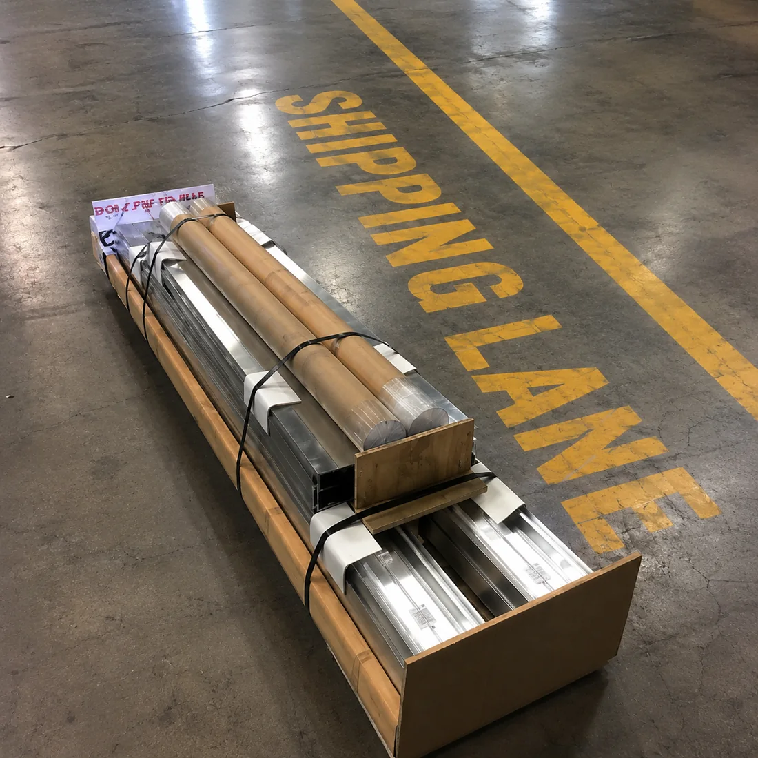Packed DIY LED sign kit banded to a crate with aluminum frame sections and retainers, staged in the shipping lane ready to ship